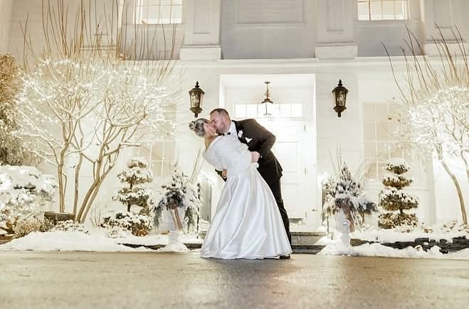 Couple kissing in snow with string lights