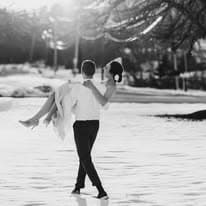 Groom carrying bride in snow