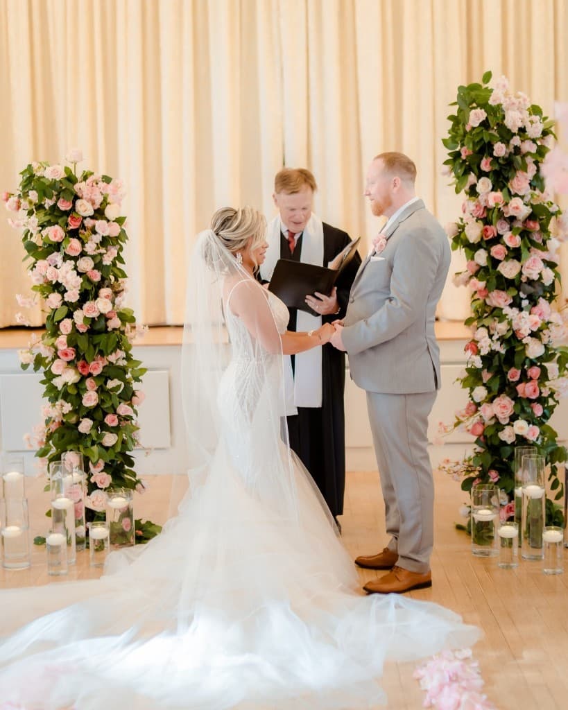 Indoor ceremony with pink floral columns at The Commons 1854