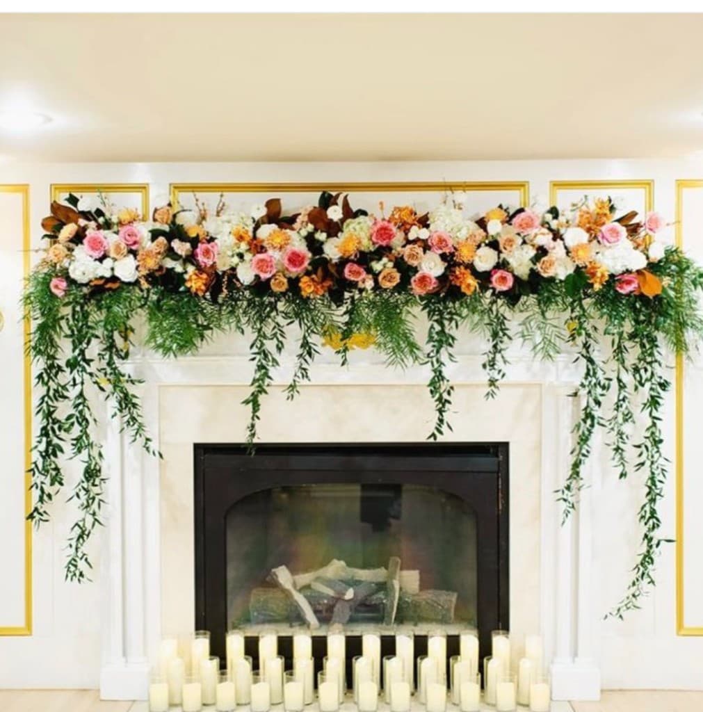 Fireplace decorated with fall florals for ceremony