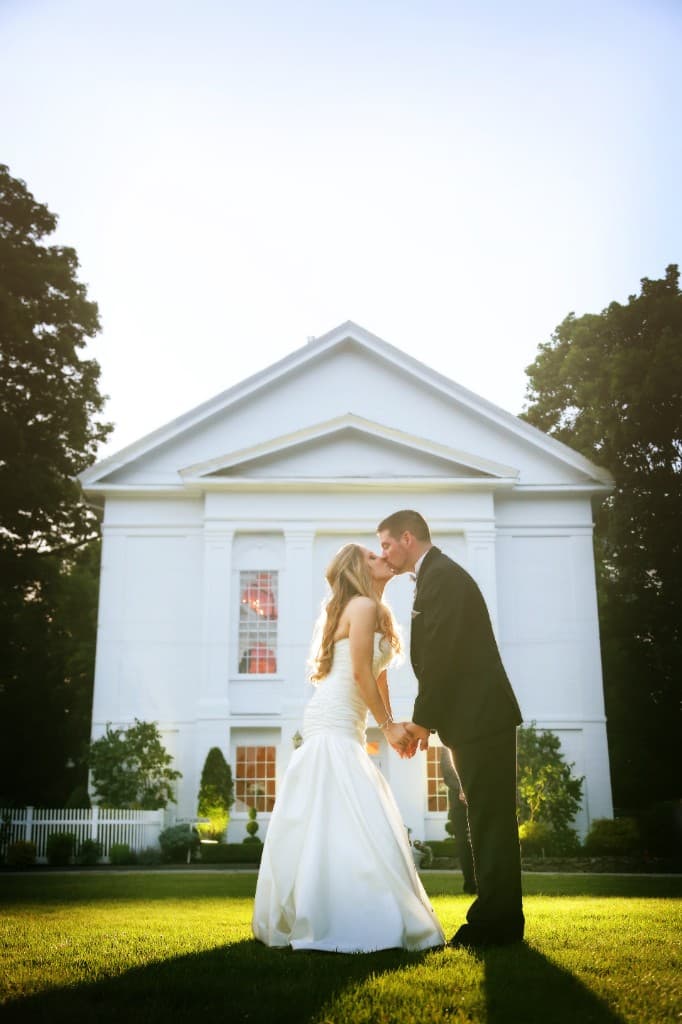 Couple kissing on the lawn with The Commons 1854 building at golden hour sunset